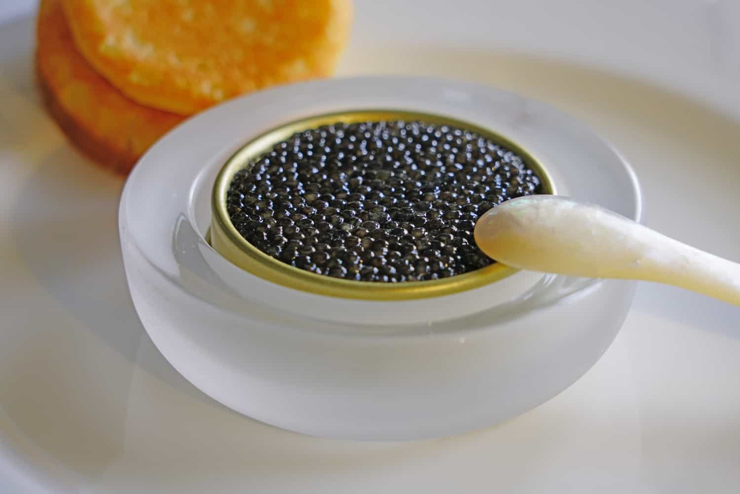 A tin of black sturgeon caviar with blinis and a mother-of-pearl